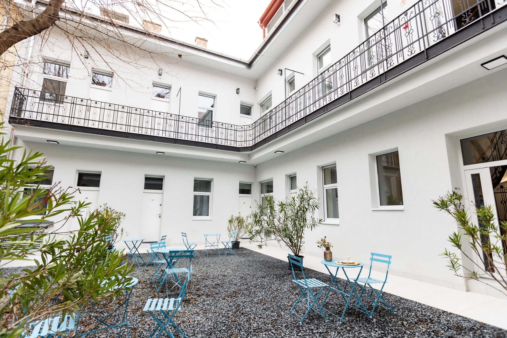 The shared courtyard at Gát utca 19, with planting and café seating